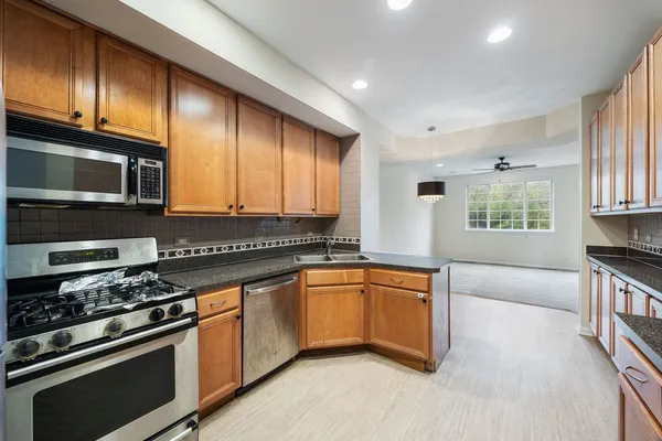 a kitchen with stainless steel appliances granite countertop a stove a sink and a microwave