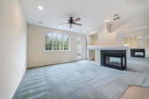 an empty room with windows and a fireplace