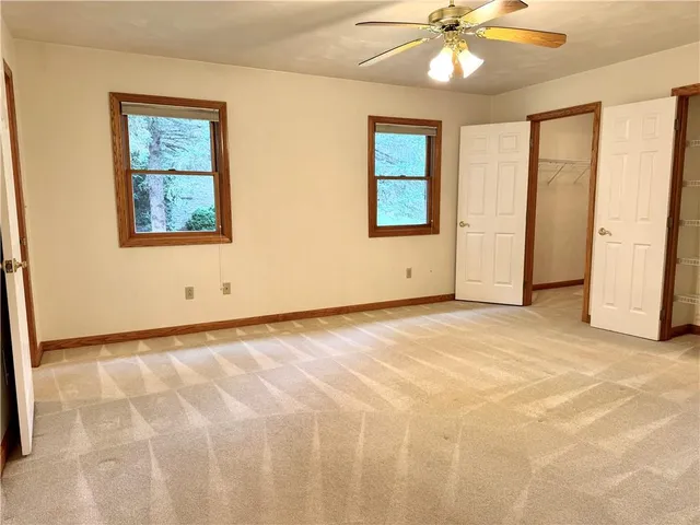 an empty room with windows and fan