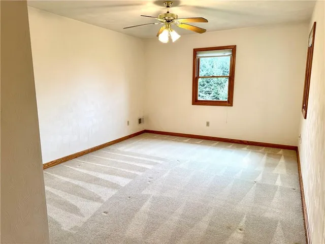 an empty room with a chandelier fan and windows