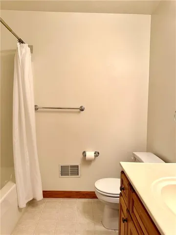 a white toilet sitting next to a white sink and vanity