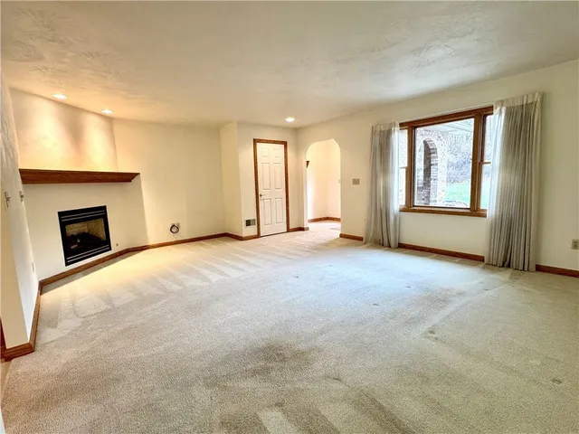 an empty room with windows and fireplace