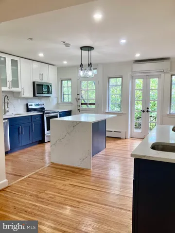 a large kitchen with granite countertop a large counter top stainless steel appliances a window and cabinets