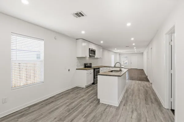 a view of a kitchen with kitchen island a sink wooden floor and a large window