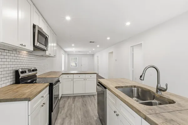 a kitchen with granite countertop a sink stainless steel appliances and cabinets