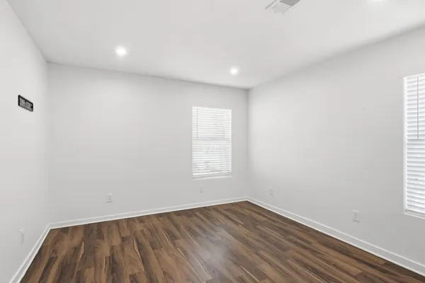 a view of an empty room with wooden floor and window