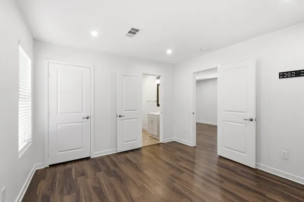a view of an empty room with wooden floor and closet