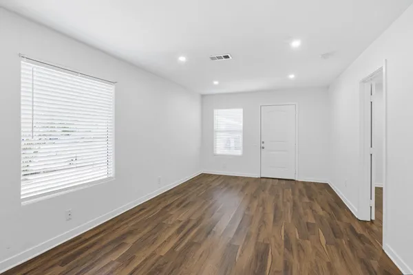 an empty room with wooden floor and windows
