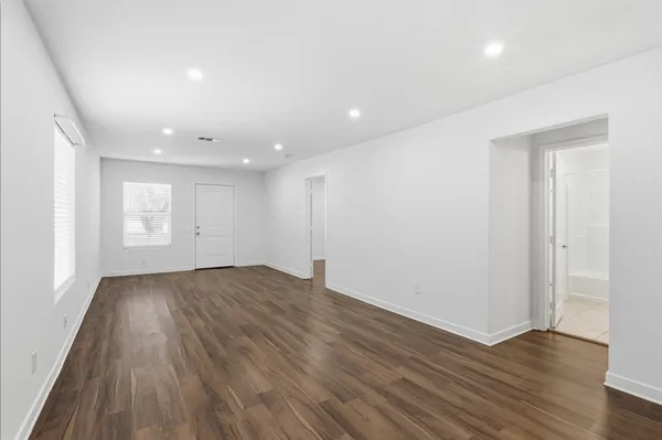 a view of an empty room with wooden floor and closet