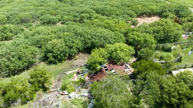 an aerial view of residential house with outdoor space and trees all around