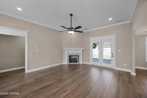 a view of a livingroom with wooden floor a fireplace a ceiling fan and windows