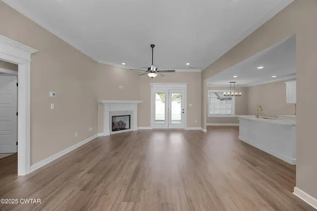 an empty room with wooden floor fireplace and windows