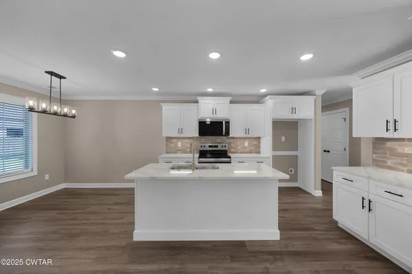 a large kitchen with stainless steel appliances granite countertop a stove oven and a white refrigerator