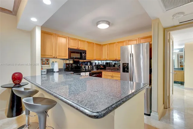 a kitchen with stainless steel appliances kitchen island granite countertop a refrigerator a stove top oven a sink and dishwasher