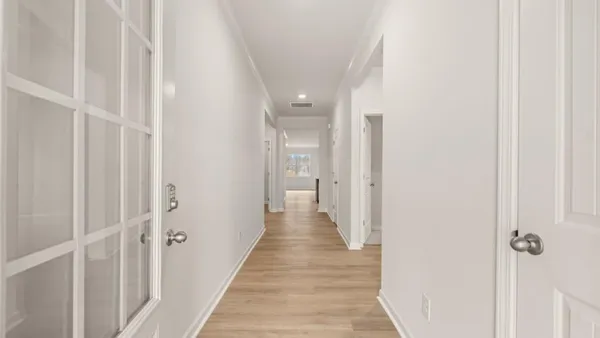 a view of a hallway with wooden floor and a shower