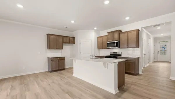 a kitchen with stainless steel appliances a stove top oven a sink a refrigerator white cabinets and wooden floor