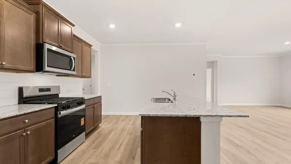 a kitchen with stainless steel appliances granite countertop a stove a sink and a microwave