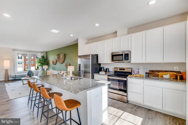 a kitchen with stainless steel appliances granite countertop a stove top oven a sink a dining table and chairs