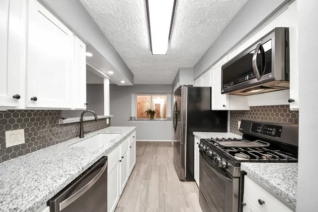 a kitchen with stainless steel appliances granite countertop a stove microwave sink and refrigerator