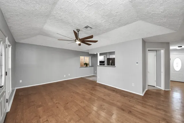 an empty room with wooden floor and windows