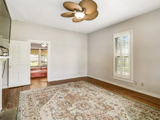 a view of an empty room with window and wooden floor