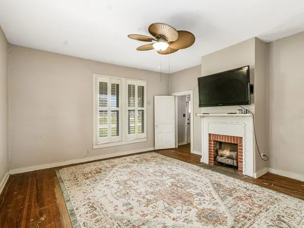 a view of an empty room with window and wooden floor