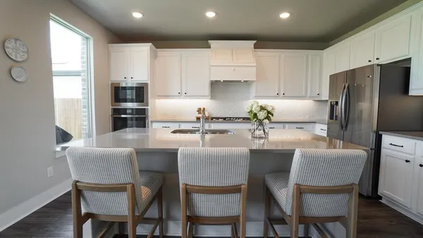 a kitchen with stainless steel appliances granite countertop a sink a stove and white cabinets