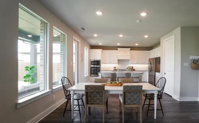 a dining room with stainless steel appliances a dining table and chairs