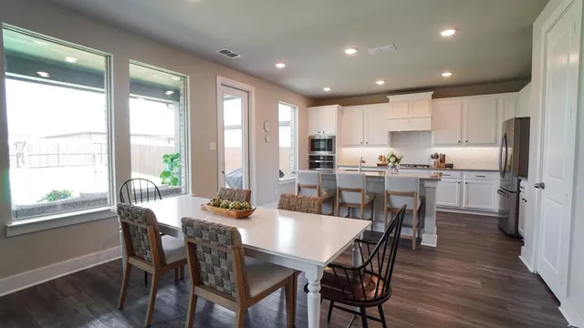 a kitchen with stainless steel appliances a dining table chairs refrigerator and microwave