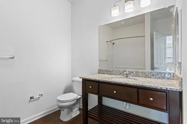a bathroom with a granite countertop toilet sink and mirror