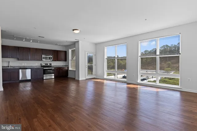 a view of an empty room with kitchen and a window