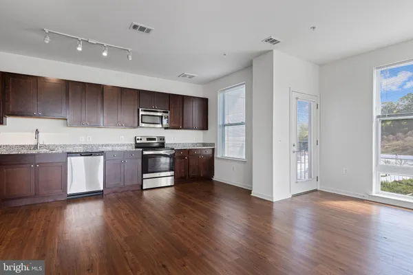 a kitchen with granite countertop wooden floors stainless steel appliances and sink
