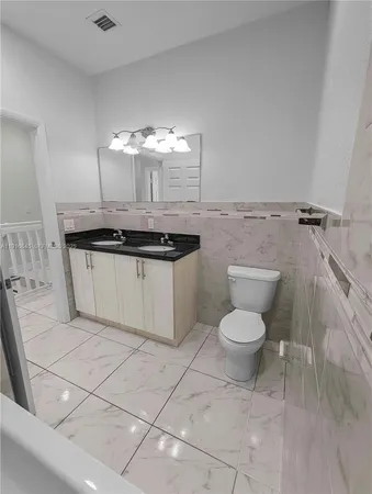 a bathroom with a granite countertop toilet a sink and a mirror