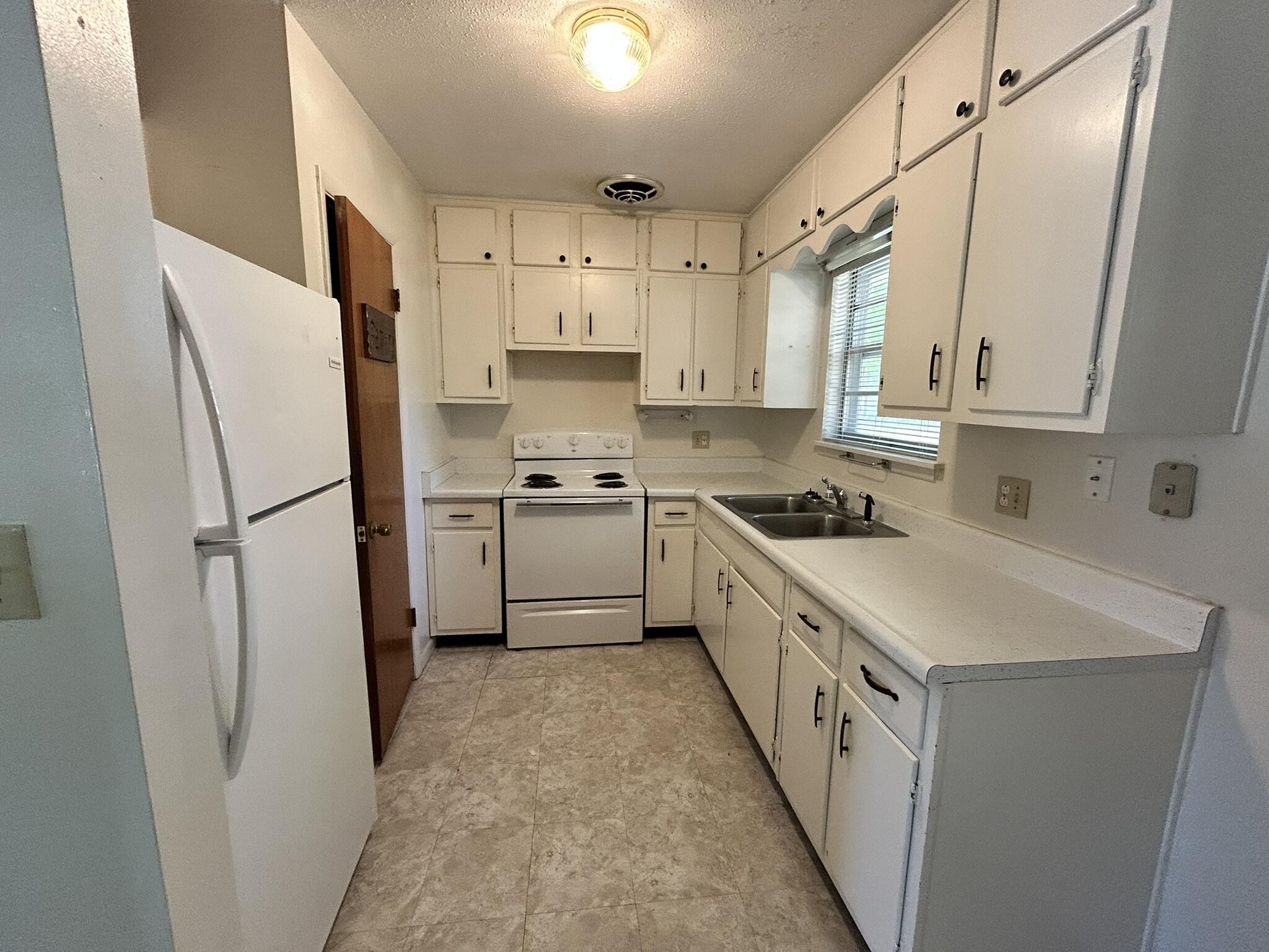 205 Powell Drive Crestview, FL 32536 - Photo 4 of 12 a kitchen with white cabinets and white appliances
