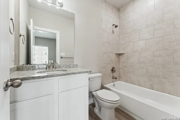 a bathroom with a granite countertop sink a toilet and bathtub
