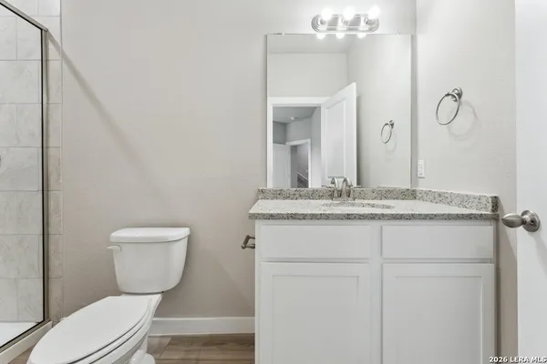 a bathroom with a granite countertop toilet sink and mirror