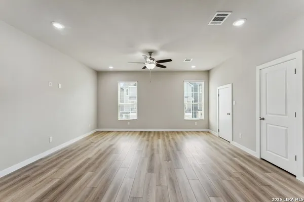 a view of an empty room with a window and wooden floor