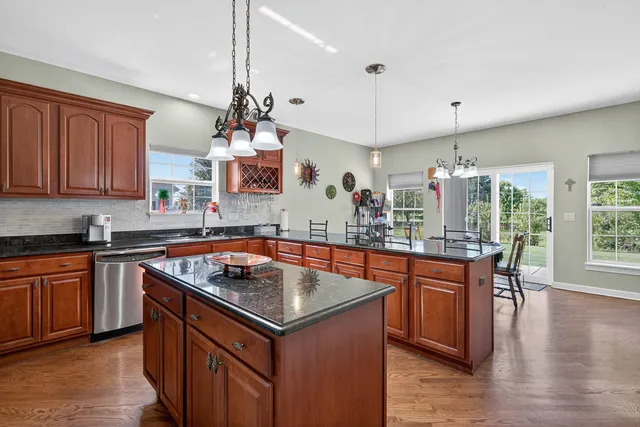 a kitchen with a stove a sink dishwasher a kitchen island with wooden cabinets and floor
