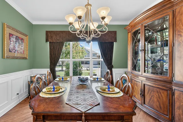 a view of a dining room with furniture a chandelier and large windows