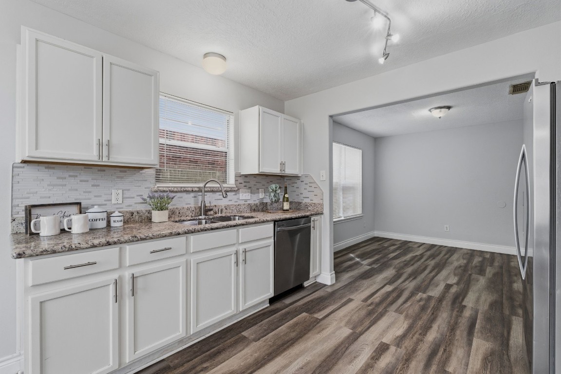 1427 Hade Falls Lane Houston, TX 77073 - Photo 9 of 31 This kitchen features modern white cabinetry, a sleek tile backsplash, and stainless steel appliances.