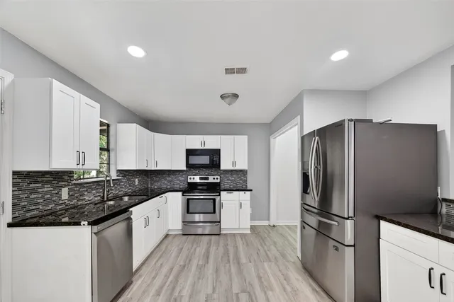 a kitchen with kitchen island granite countertop stainless steel appliances a sink a refrigerator a stove a microwave and cabinets