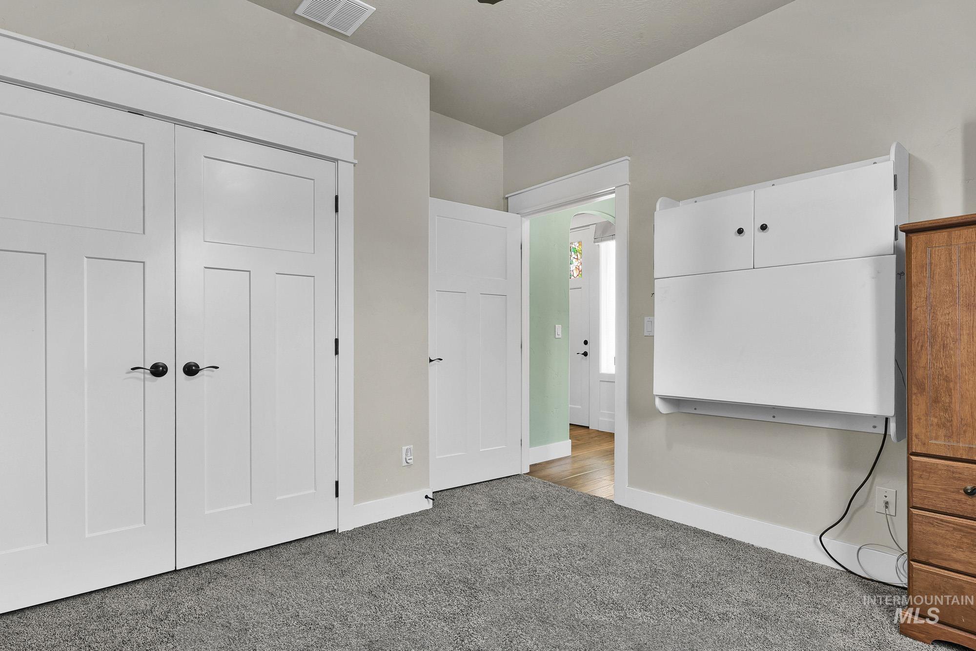 220 South Wildgrass Way Star, ID 83669 - Photo 31 of 50 Room featuring a built-in wall bed with an integrated desk, a ceiling fan with light fixture, a window with white trim, and light gray wall-to-wall carpeting