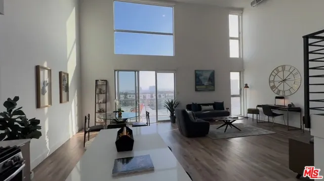 a living room with furniture a large window and wooden floor