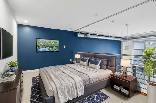 a bedroom with a bed a couch and a flat screen tv