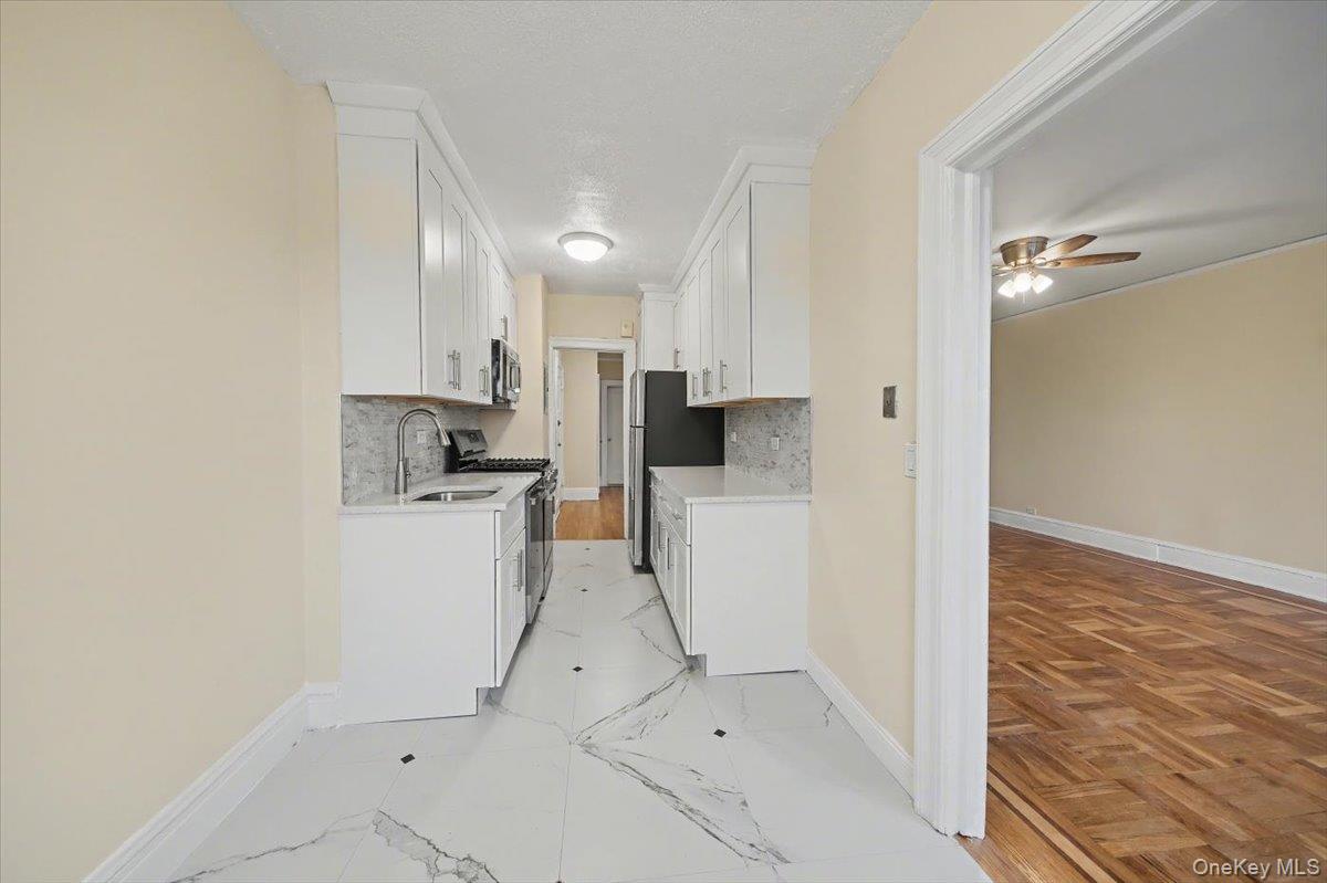 127 Garth Road, Unit 5D Scarsdale, NY 10583 - Photo 12 of 20 a kitchen with white cabinets and white appliances