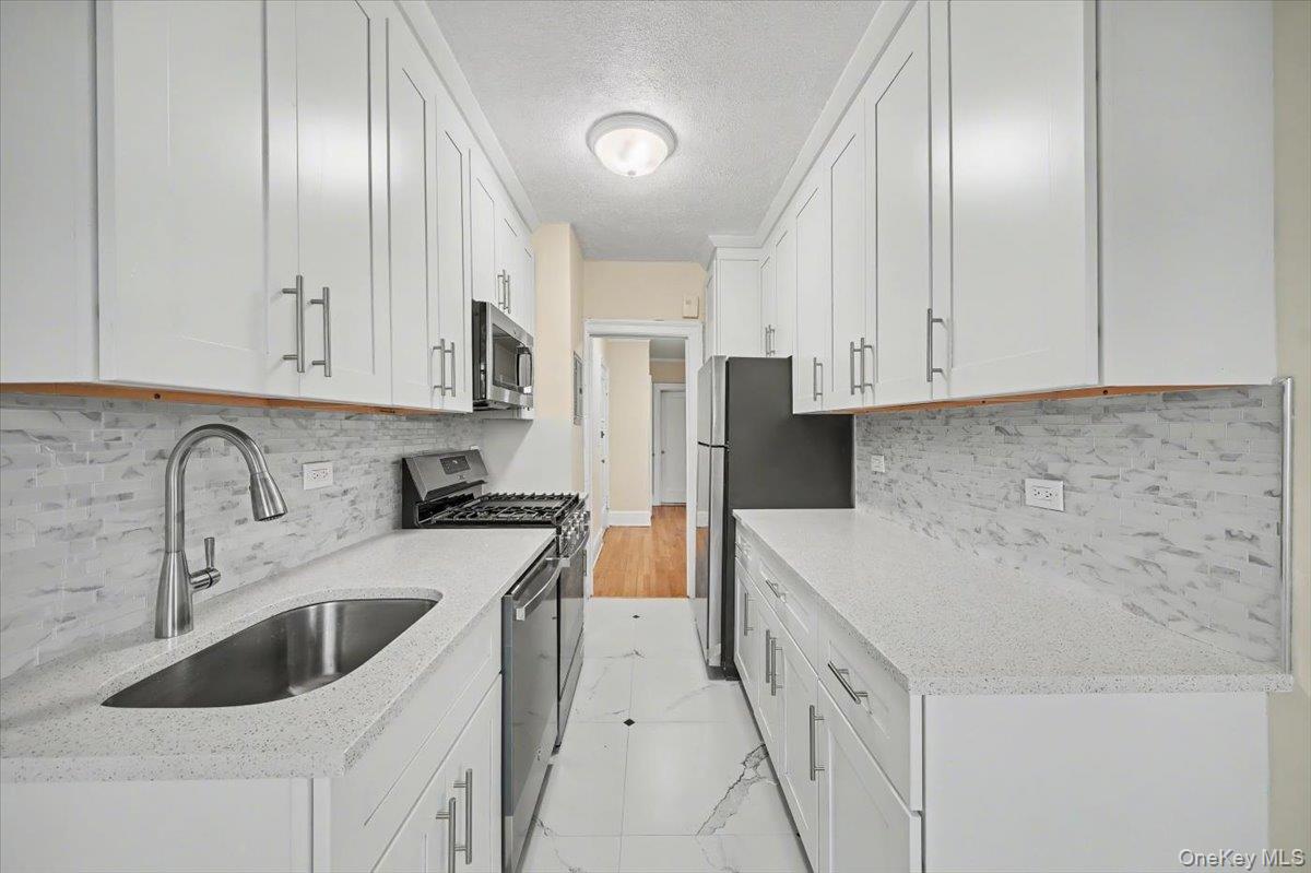127 Garth Road, Unit 5D Scarsdale, NY 10583 - Photo 8 of 20 a kitchen with stainless steel appliances granite countertop a sink stove and refrigerator
