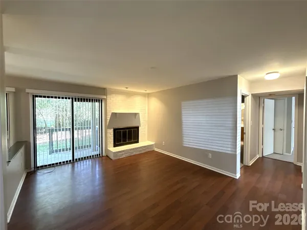 an empty room with floor to ceiling window and wooden floor