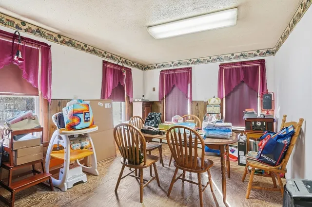 a view of a dining room with furniture one side kitchen view and wooden floor