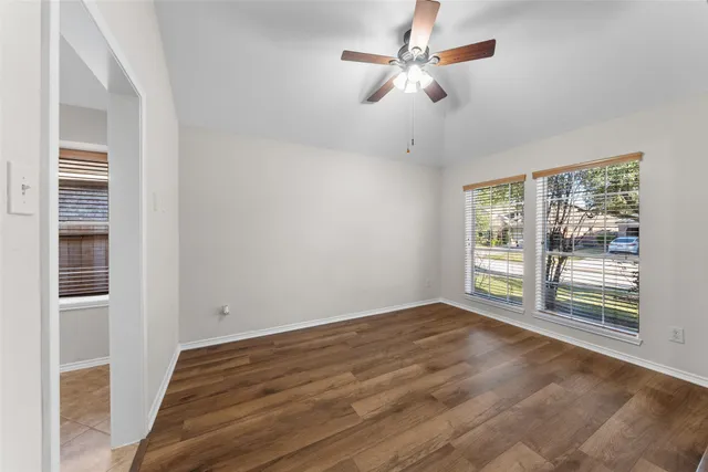 a view of empty room with wooden floor and fan