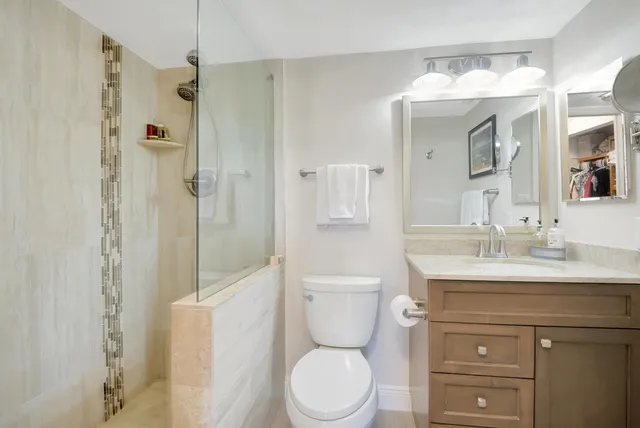 a bathroom with a toilet a sink a mirror a vanity and shower